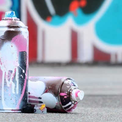 Several used spray cans with pink and white paint and caps for spraying paint under pressure is lies